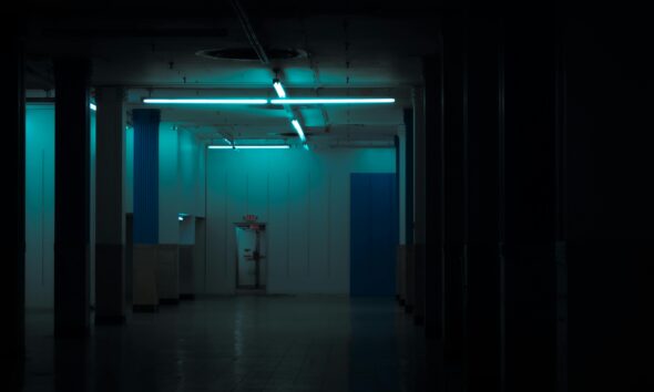 Shadowy abandoned room with a camera in the foreground, evoking a viral TikTok found-footage horror aesthetic.